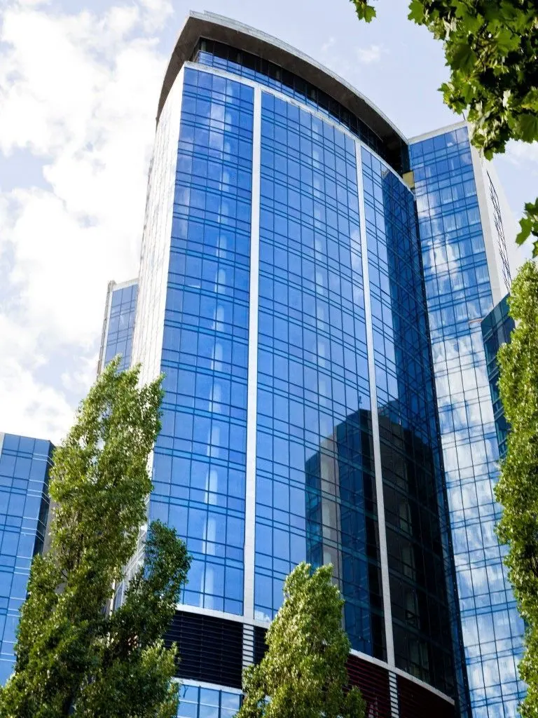 A blue glass tower seen from street level
