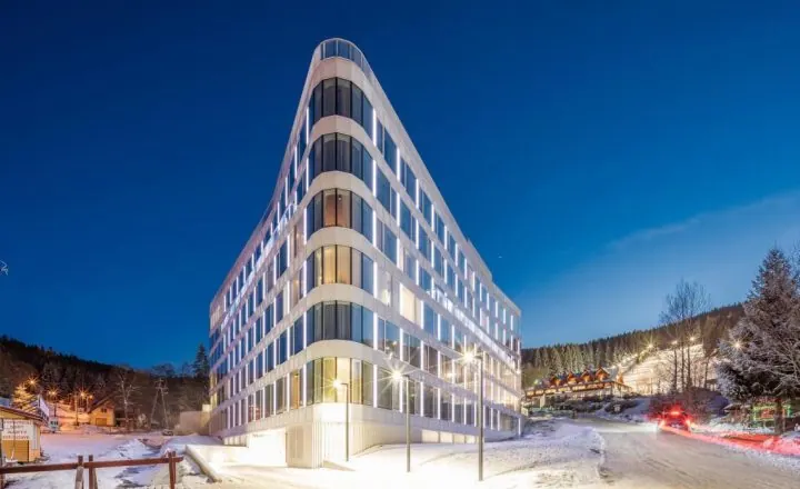A well-lit hotel building A well-lit hotel building in a triangular form of architecture, standing out in a winter forest background